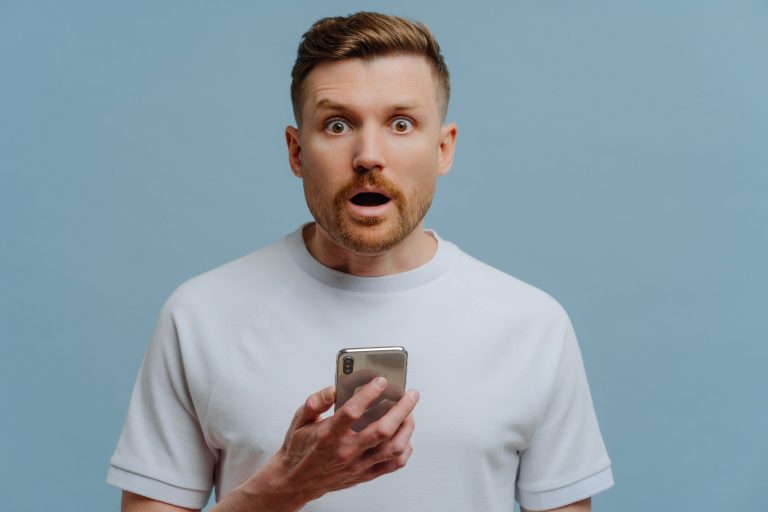 Surprised man reading unexpectable news on mobile phone